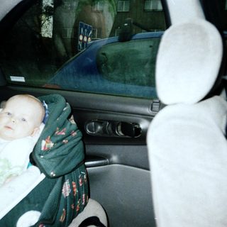 Baby secured in car seat with blanket.