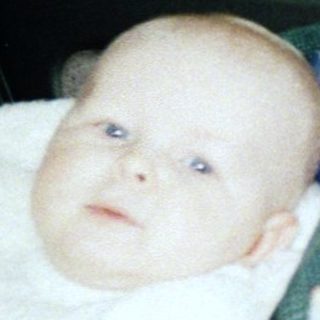 Baby secured in car seat with blanket.