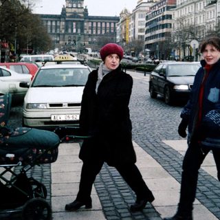 Two women walking with a stroller in a city street.