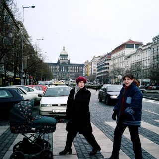 Two women walking with a stroller in a city street.