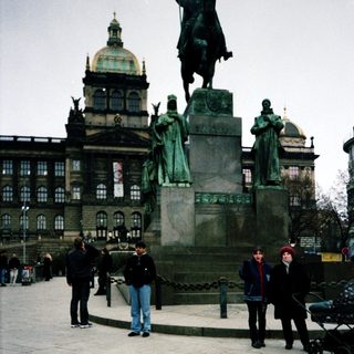 Statue square with historical monument and people.