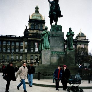 People walking near Prague Castle and statue.