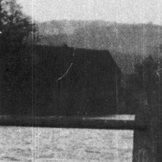 Scenic lake view with leafless trees and fence.