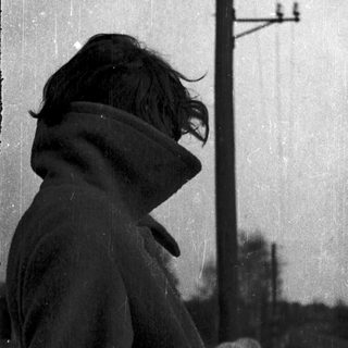 Silhouette of person wearing hooded coat against rain.