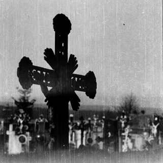 Ornate cross in a cemetery against sky.