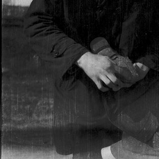 Person holding a round object while sitting in rain.