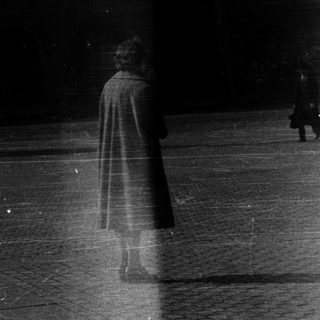 Blurred figures walking in rain or snow.