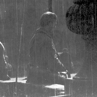 Reflection of three seated people in rainy glass.