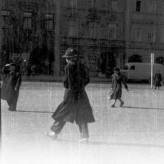Vintage street scene with people walking in rain.