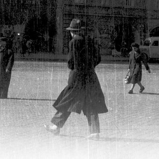 Vintage street scene with people walking in rain.