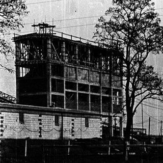 A person standing on a bridge near a water tower.