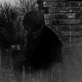 A person in rain near brick wall.