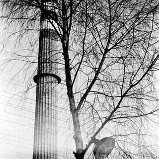 Tall tower with lattice structure beside bare trees.