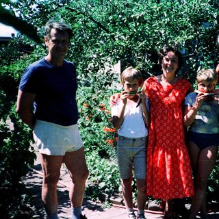 Family posing outdoors with watermelons.