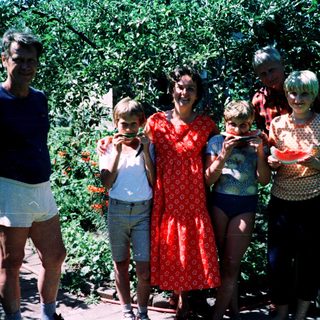 Family posing outdoors with watermelons.