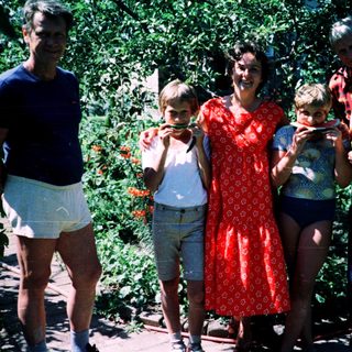 Family posing outdoors with watermelons.