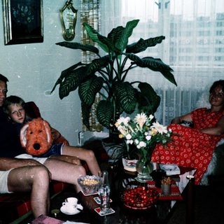Family indoors with teddy bear, enjoying a relaxed moment.