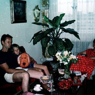 Family indoors with teddy bear, enjoying a relaxed moment.