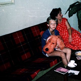 Family indoors with teddy bear, flowers, and city view.