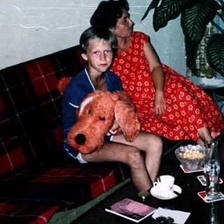 Family indoors with teddy bear, flowers, and city view.