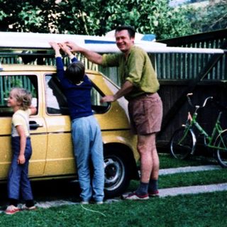 Family posing with vintage car and surfboard.