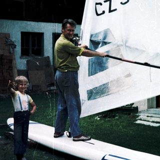 Man and child preparing sailboard with "CZ929" sail.