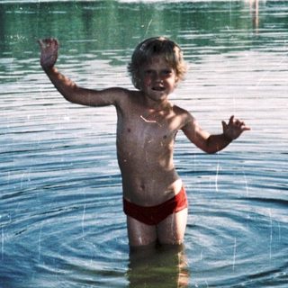 Joyful child playing in shallow lake water.