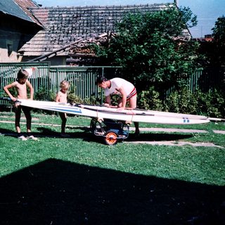 Family preparing surfboard for beach outing.