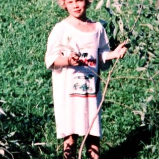 Child holding flowers in a garden.
