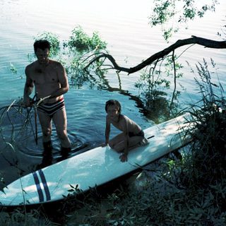 Two people by water with paddleboard.