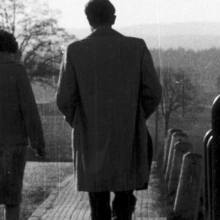 Two people walking together outdoors on a paved path.