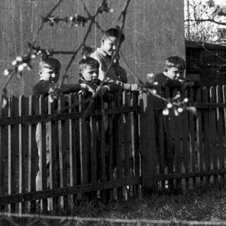 Four children playing outside near a fence.