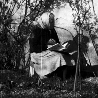 Person reading outdoors near a building.