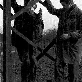 Two men constructing or repairing metal framework.