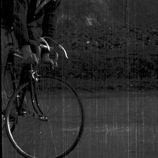 Young man riding vintage bicycle outdoors.