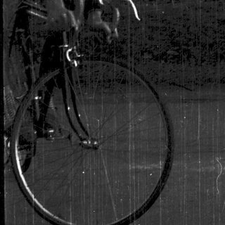 Young man riding vintage bicycle outdoors.