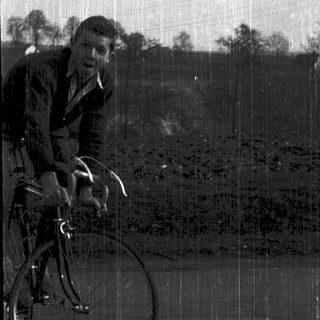 Young man riding vintage bicycle outdoors.