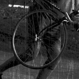 Person carrying a bicycle while running outdoors.