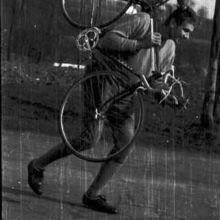 Person carrying a bicycle while running outdoors.