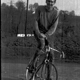 Young man smiling while sitting on a road bike.