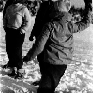 People playing in snow, throwing snowballs.