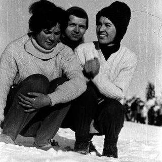 Three people posing happily in winter attire on snow.