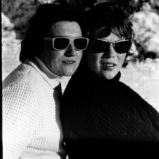 Two women wearing sunglasses and casual attire outdoors.