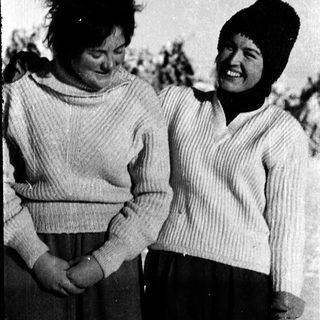 Two women smiling outdoors in winter attire.