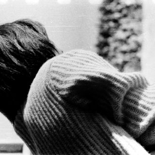 Child leaning on window sill, looking outside.