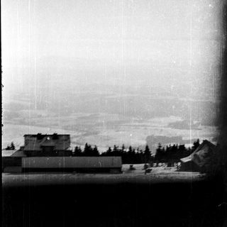 Industrial facility with smokestacks in snowy landscape.