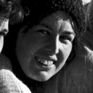 Three people smiling together outdoors in winter attire.