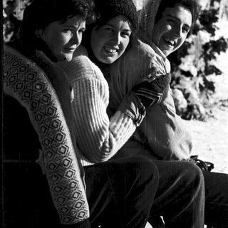 Three people smiling together outdoors in winter attire.