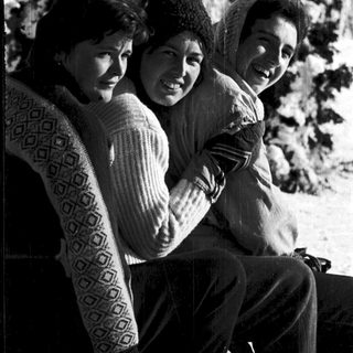 Three people smiling together outdoors in winter attire.