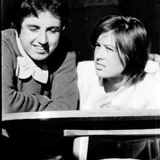 Two people smiling and interacting indoors.
